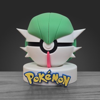 Pokéball Gardevoir face : coiffe verte, visage blanc et corne rouge centrale sur socle blanc.