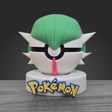 Pokéball Gardevoir face : coiffe verte, visage blanc et corne rouge centrale sur socle blanc.